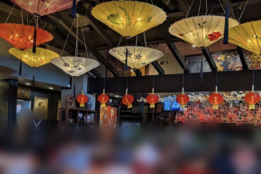 Dining room at Qi Austin with painted paper parasols and red lanterns over the bar